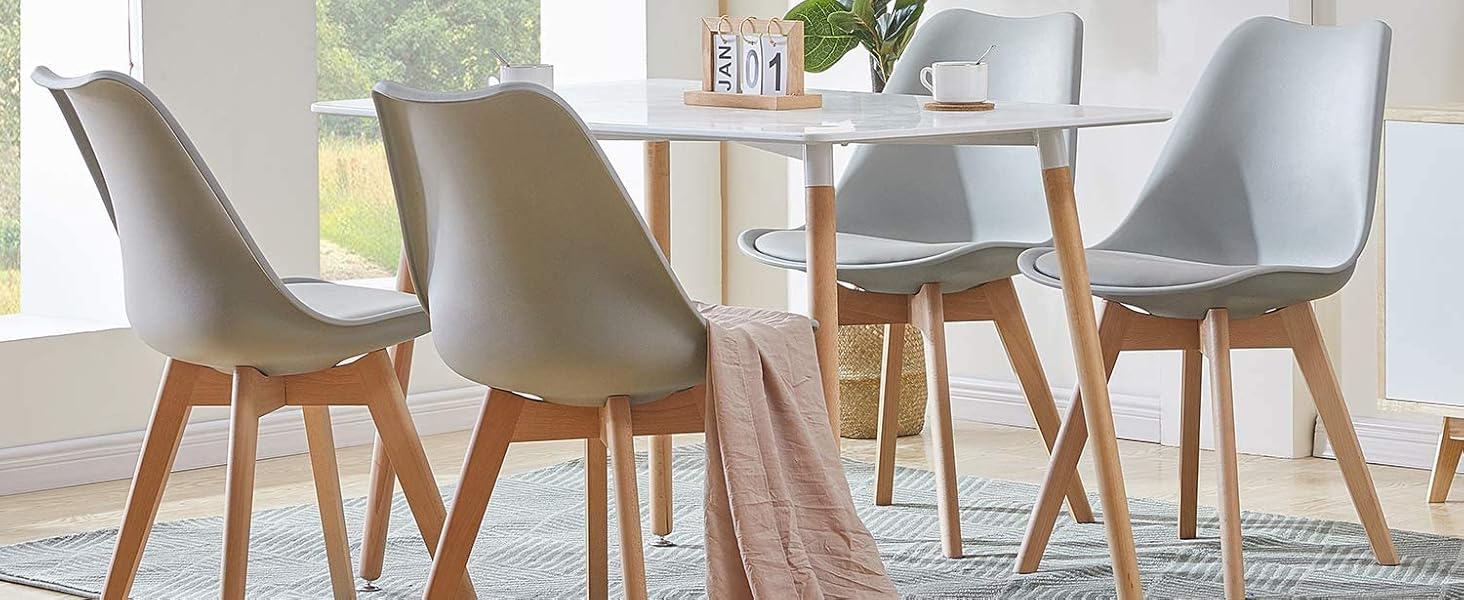 avec table blanche et quatre chaises grises avec pieds en bois. Plante en pot près de la fenêtre, jetez une couverture sur une chaise