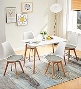avec table rectangulaire blanche et quatre chaises assorties. Pieds en bois, chambre lumineuse avec décoration murale et tapis.