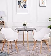 avec table ronde noire et trois chaises blanches en forme de coquille avec pieds en bois, disposés dans une pièce lumineuse avec art mural