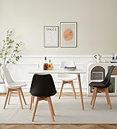 Salle à manger moderne avec table blanche, styles de chaises mixtes, art mural encadré et plante décorative. Esthétique épurée et minimaliste.