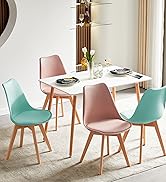 avec table rectangulaire blanche et quatre chaises. Deux chaises roses et deux chaises bleu sarcelle avec pieds en bois. Table dressée pour un repas.