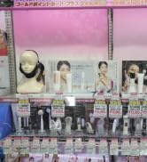 Présentation de plusieurs produits d'écouteurs dans des emballages en plastique, disposés en rangées sur une étagère de vente au détail sur fond rose