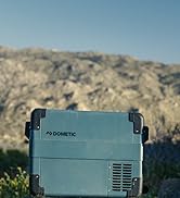 de couleur bleu clair, avec grilles de ventilation visibles. Présenté en extérieur sur un fond rocheux ressemblant à un désert