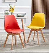 Chaises de salle à manger modernes avec sièges en plastique moulé rouge et jaune, avec pieds en bois. Chaises présentées dans un décor de salle à manger avec une petite table et des éléments décoratifs.